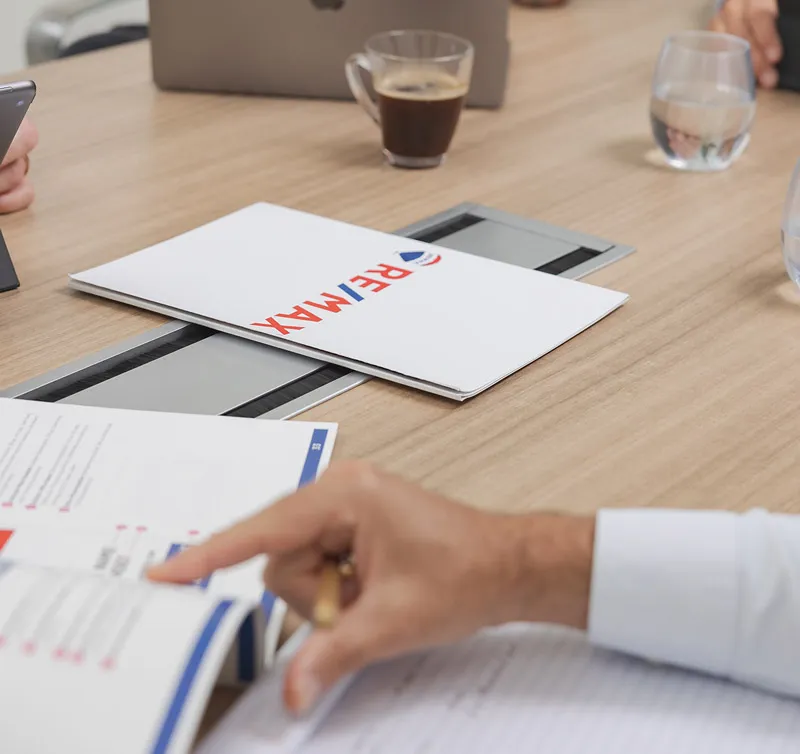 A buyer going through a RE/MAX brochure at a meeting table